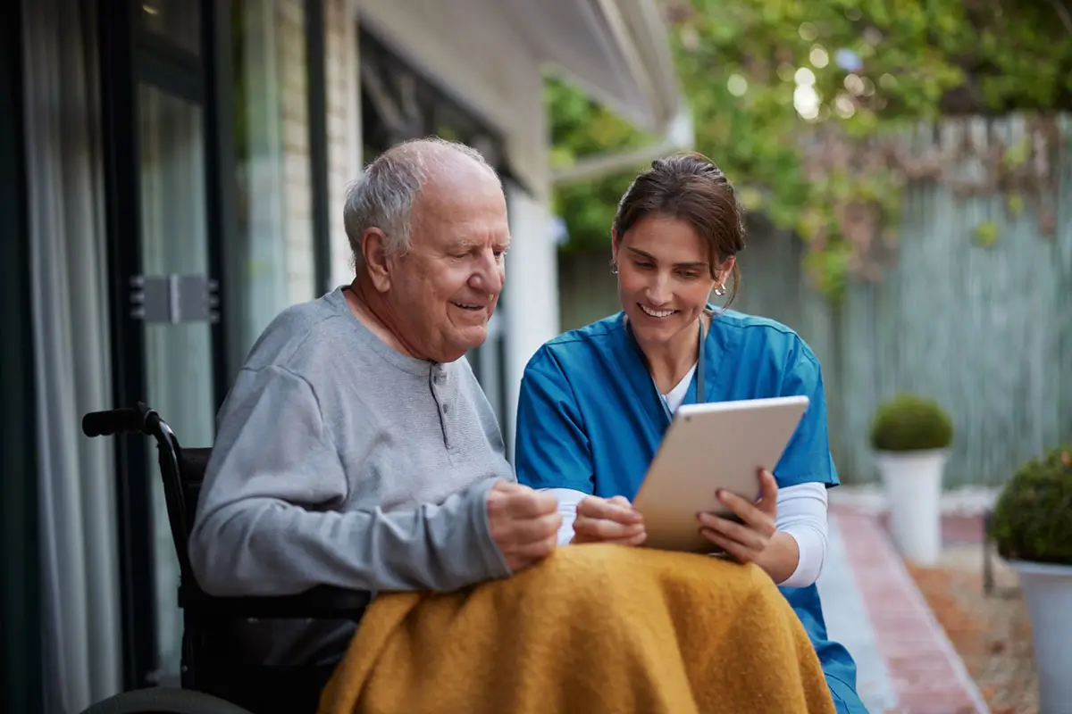 Friendly nurse and senior man on wheelchair using digital tablet Friendly nurse and senior man on wheelchair using digital tablet